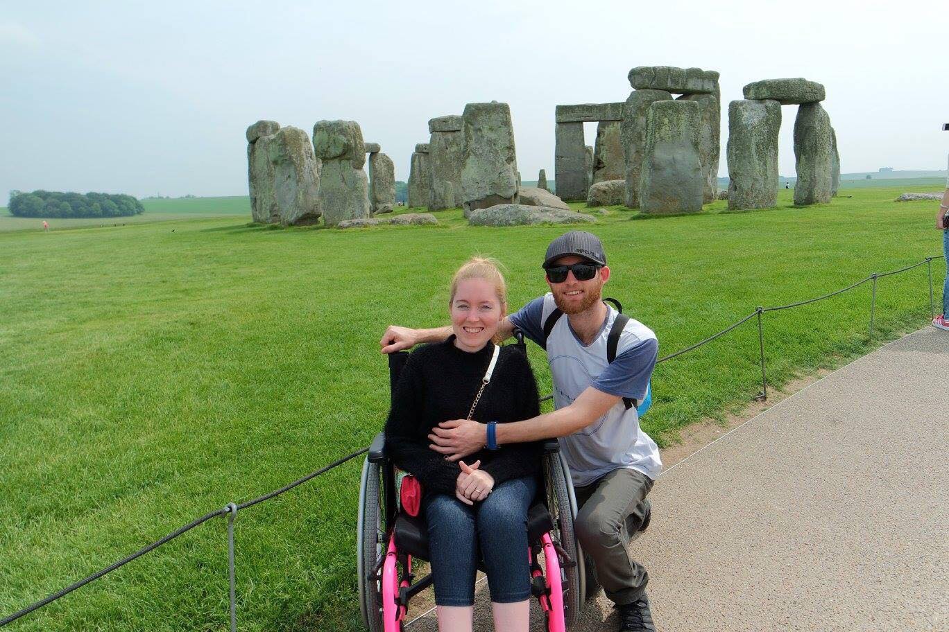 young couple pose in front of Stonehenge. 